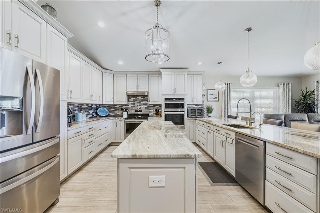 Expansive kitchen featuring a double island layout, white cabinetry, integrated stainless steel appliances, and light-toned countertops