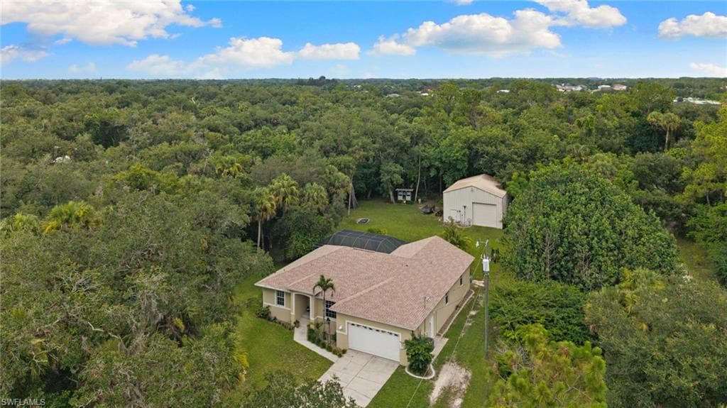Aerial perspective of a single-story residence featuring a tan exterior, an attached two-car garage, and a screened-in pool enclosure