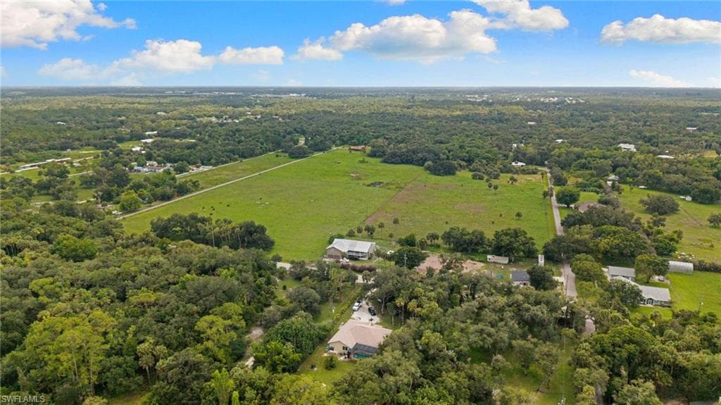 Expansive green space featuring large natural tree coverage and a clear, flat open field
