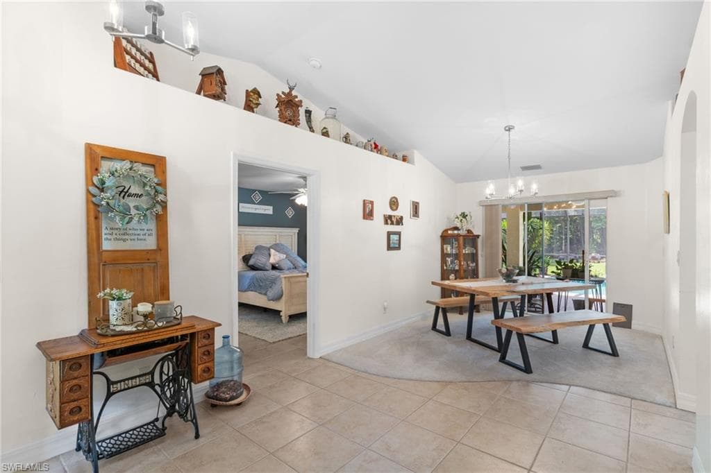 Vaulted ceiling with an upper display ledge, tile flooring, and a dining area featuring sliding glass doors to the exterior