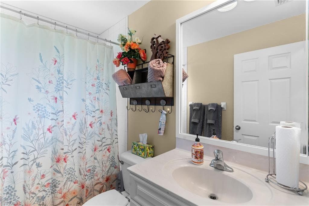 Bathroom featuring a vanity with an integrated sink, a large framed mirror, and a wall-mounted towel rack