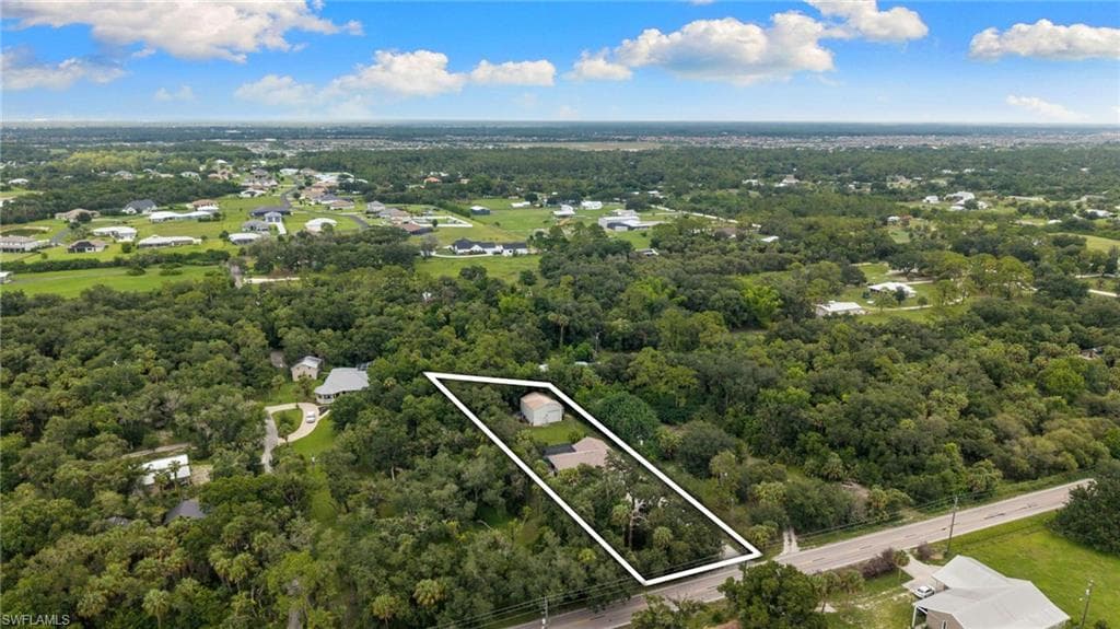Expansive wooded property with a single-story residence and additional structure, featuring direct road frontage and a generous lot size