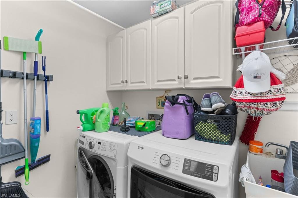 Dedicated laundry area featuring white upper cabinetry with brushed nickel hardware, a utility sink, and a wall-mounted storage rack