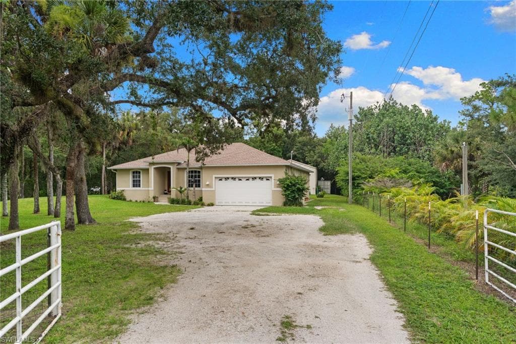 Single-story residence featuring a two-car garage, covered entry, and a gravel driveway