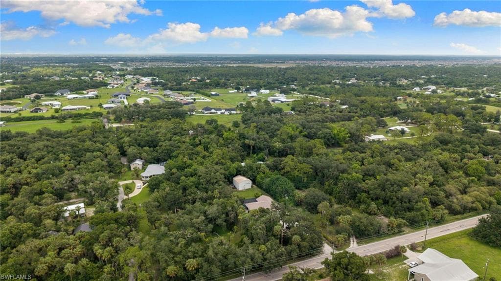Expansive landscape featuring dense tree cover and scattered residential properties, with a visible road providing access