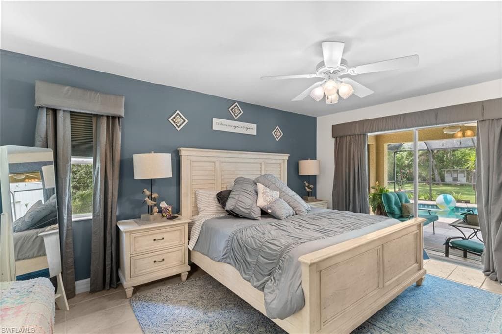 Bedroom featuring neutral tile flooring, a ceiling fan with integrated lighting, and direct access to an outdoor area through glass sliding doors