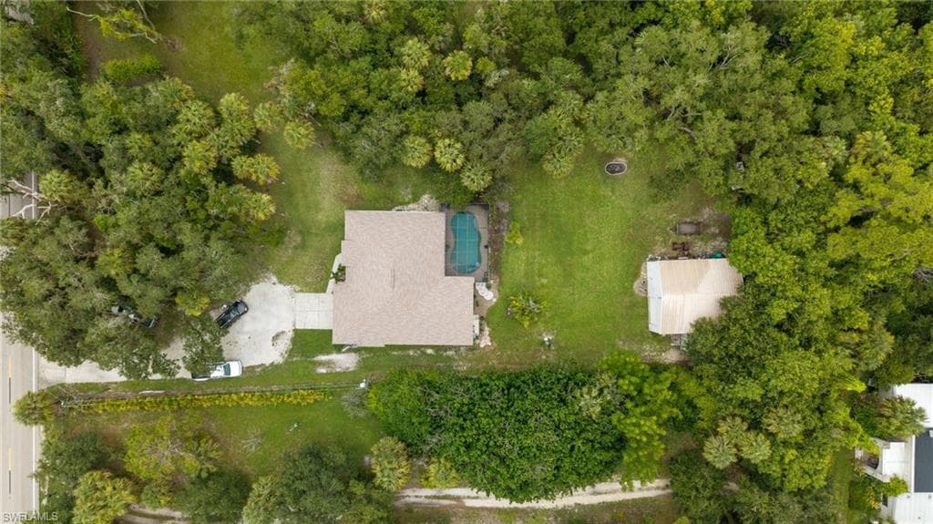 Aerial perspective of a property with a main residence, an in-ground swimming pool, and an auxiliary structure