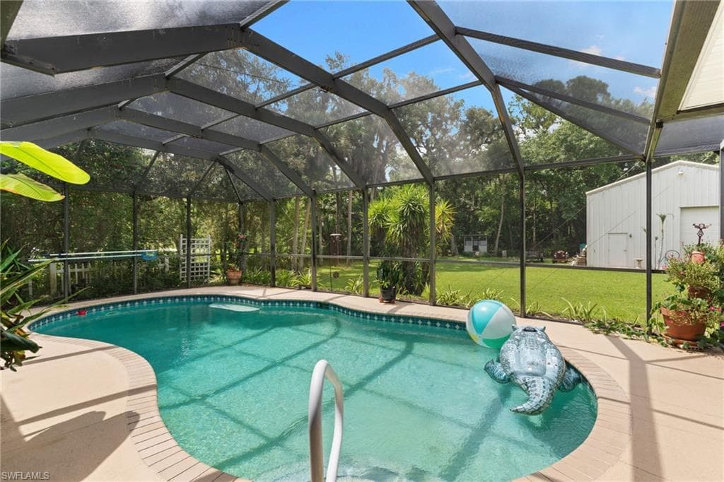 Screened pool enclosure with a free-form pool, integrated steps, and surrounding deck