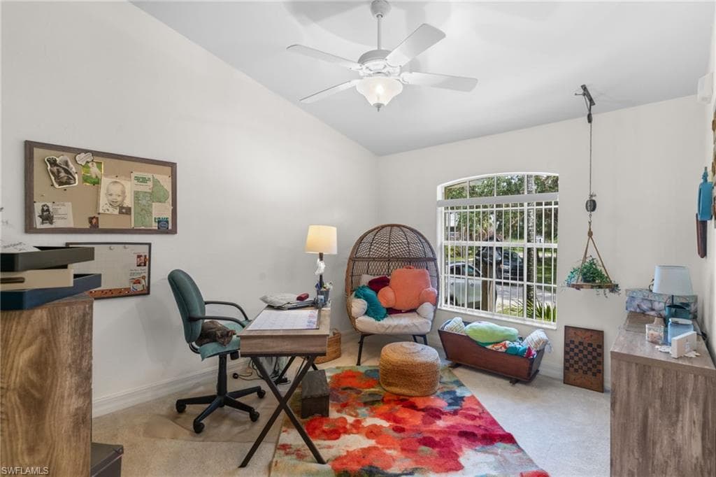 Spacious room featuring vaulted ceilings, a ceiling fan with integrated lighting, a large arched window with horizontal blinds, and neutral-toned wall paint