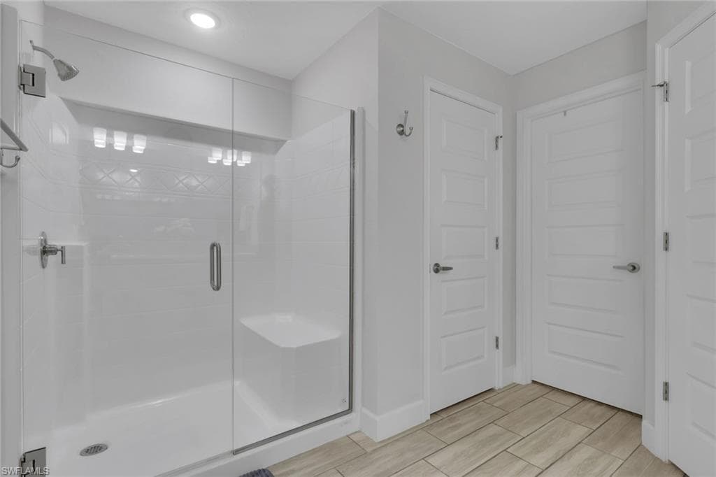 Glass-enclosed shower with a built-in bench and a tiled accent wall