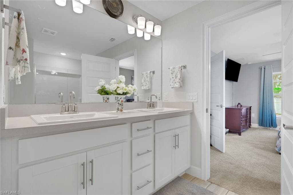 Dual vanity with white cabinetry and integrated sinks set beneath a large wall-mounted mirror