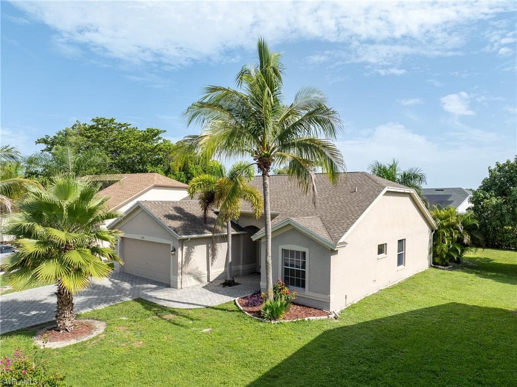 Aerial view showcasing the home's tropical landscaping and spacious corner lot.