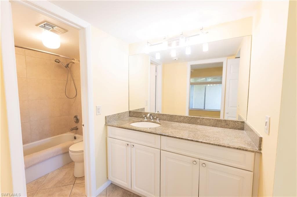 Bathroom featuring vanity, shower / tub combination, and light tile patterned floors