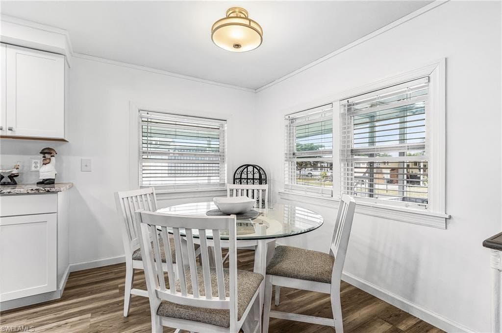 Bright dining area featuring wood-finish flooring, white walls, and a ceiling-mounted light fixture
