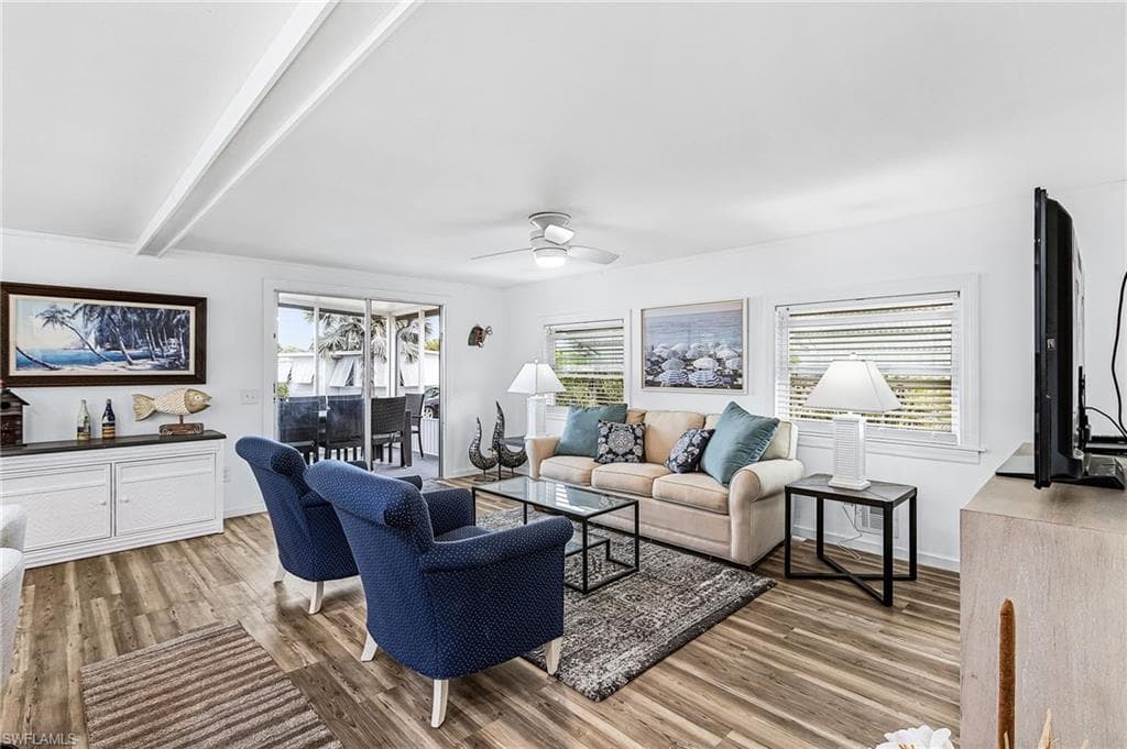 Living area featuring wood-finish flooring, white walls, and exposed ceiling beams