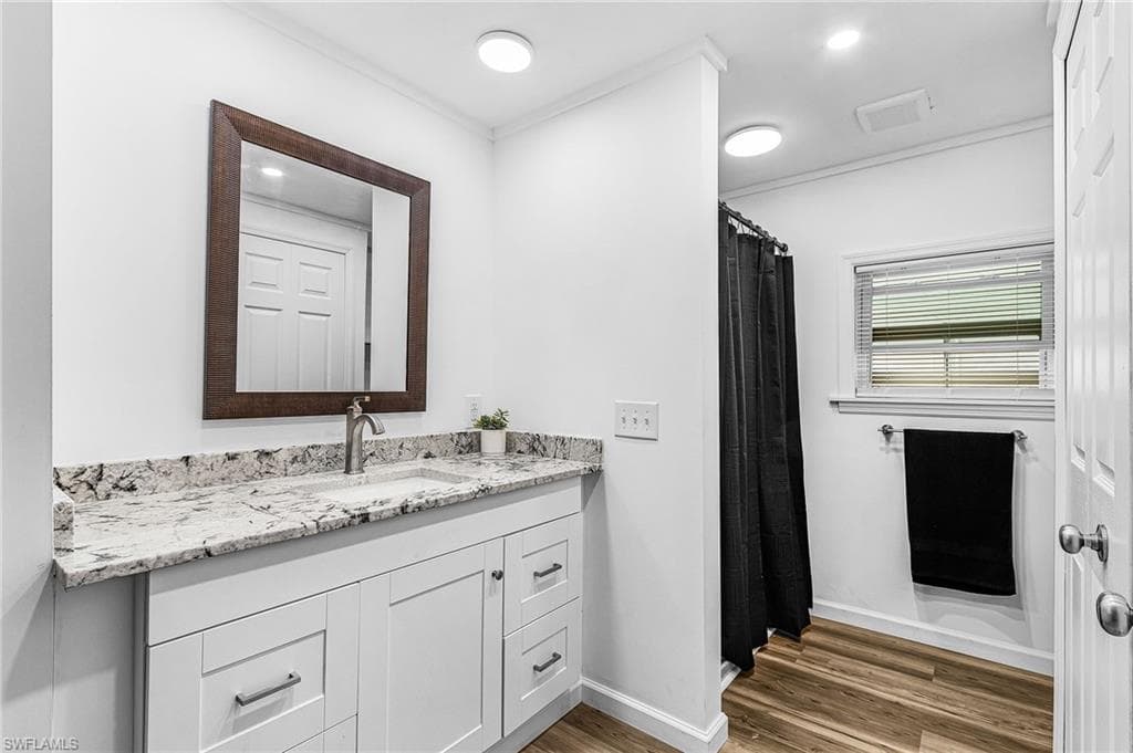 Bathroom vanity featuring a light granite countertop with an undermount sink and brushed nickel faucet
