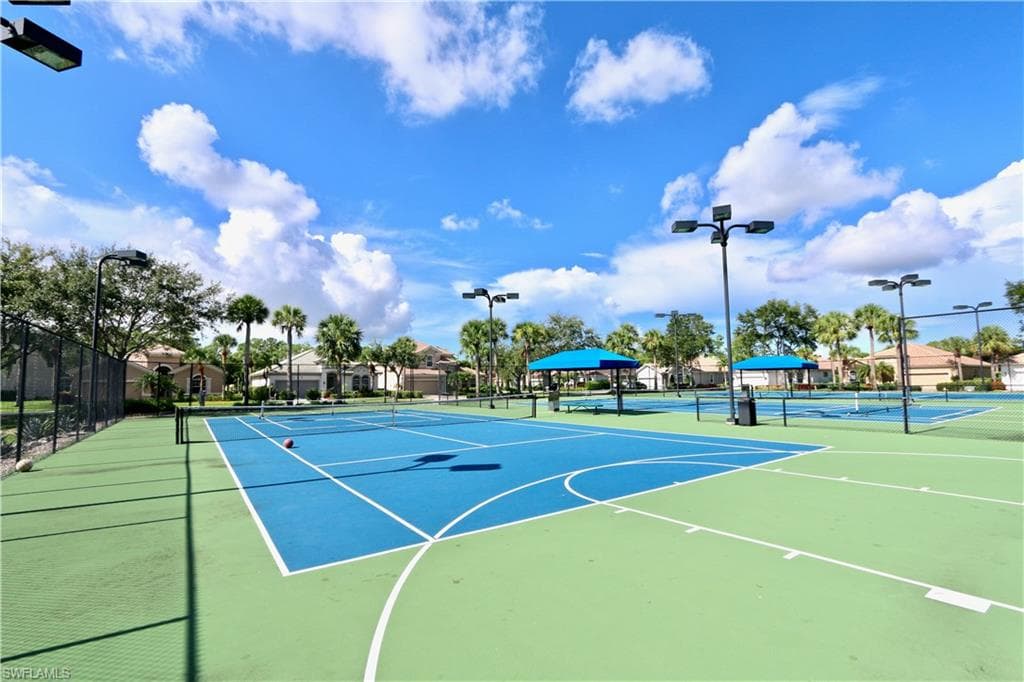 Multiple hard tennis courts featuring blue and green playing surfaces, white court lines, and perimeter fencing