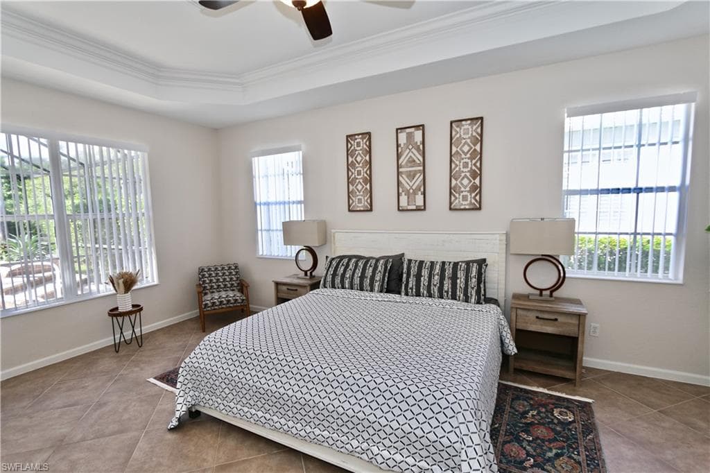 Spacious room featuring tray ceilings, a ceiling fan, and tile flooring