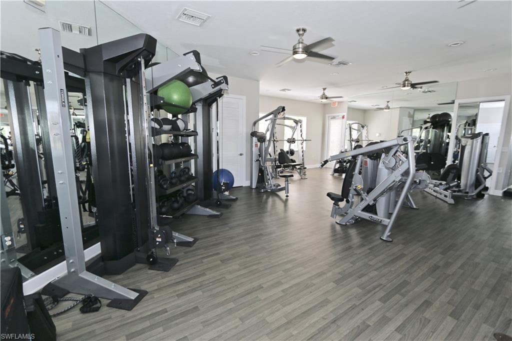 Fitness center featuring wood-finish flooring, mirrored walls, and multiple ceiling fans