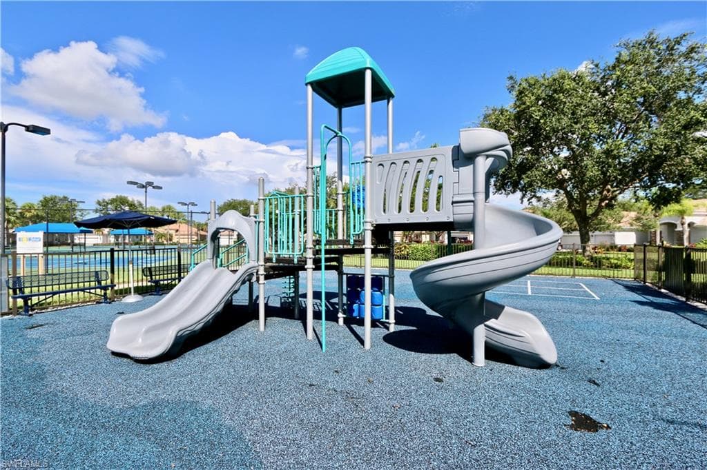 Multi-level playground structure with a spiral slide and a straight slide on a blue rubberized surface