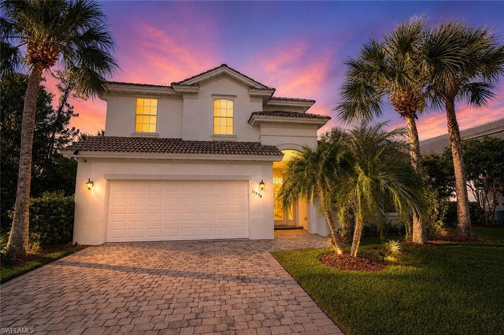 Two-story stucco home featuring a tile roof and attached garage