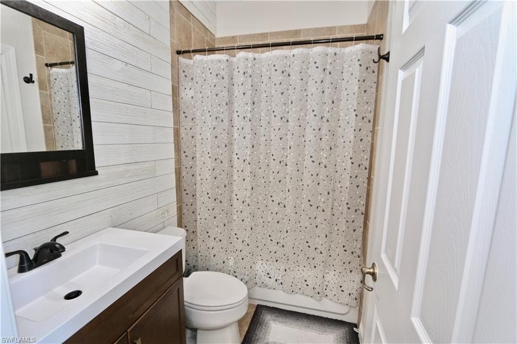 Bathroom featuring a wood-finish vanity with an integrated white sink, matte black faucet, and a framed mirror