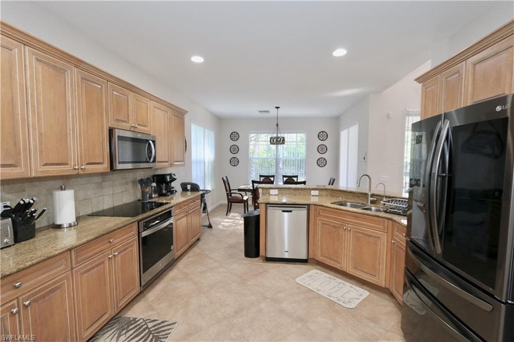 Gourmet kitchen featuring abundant wood cabinetry, granite countertops, tile flooring, stainless steel appliances, and recessed lighting