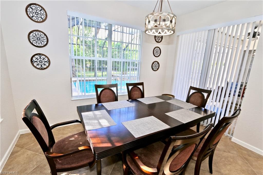 Dining area with tiled flooring, a modern chandelier, and ample natural light from a large window