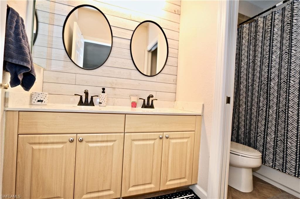 Double vanity with light wood-finish cabinetry and quartz-finish countertop