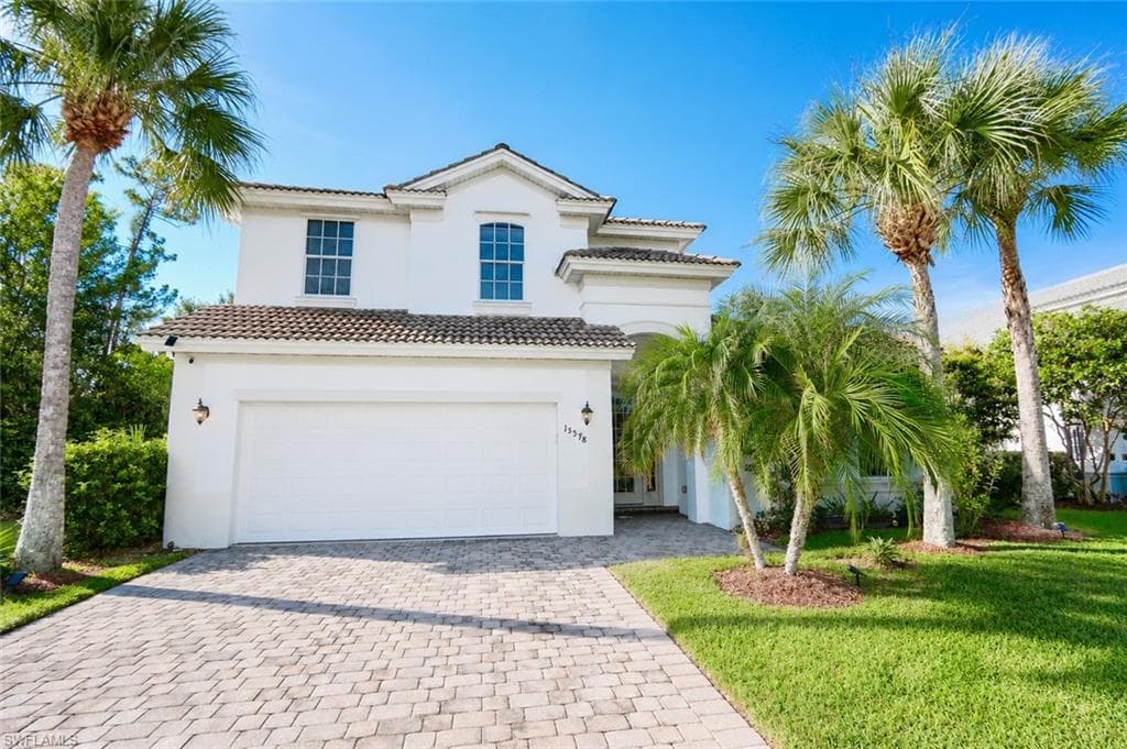 Two-story residence featuring a white stucco exterior, tile roofing, and an integrated two-car garage