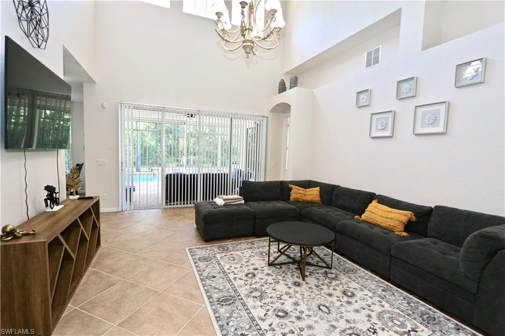 Living area featuring high ceilings, tile flooring, and large sliding glass doors providing access to an outdoor pool area