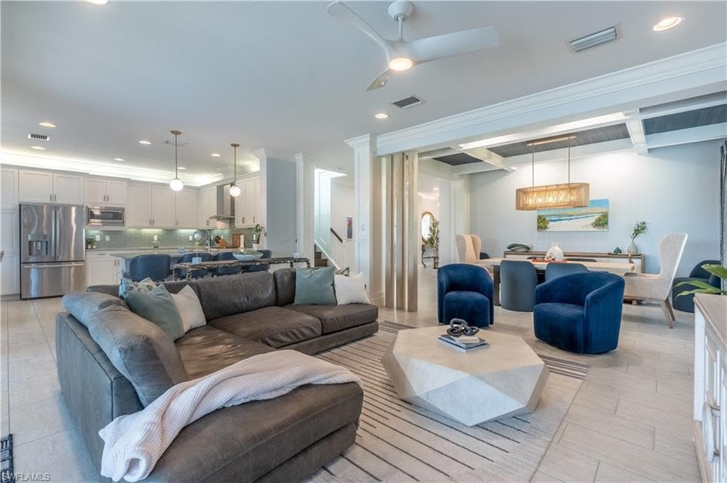 Open concept living space featuring neutral tile flooring, recessed lighting, a modern ceiling fan, and a kitchen with stainless steel appliances and white cabinetry