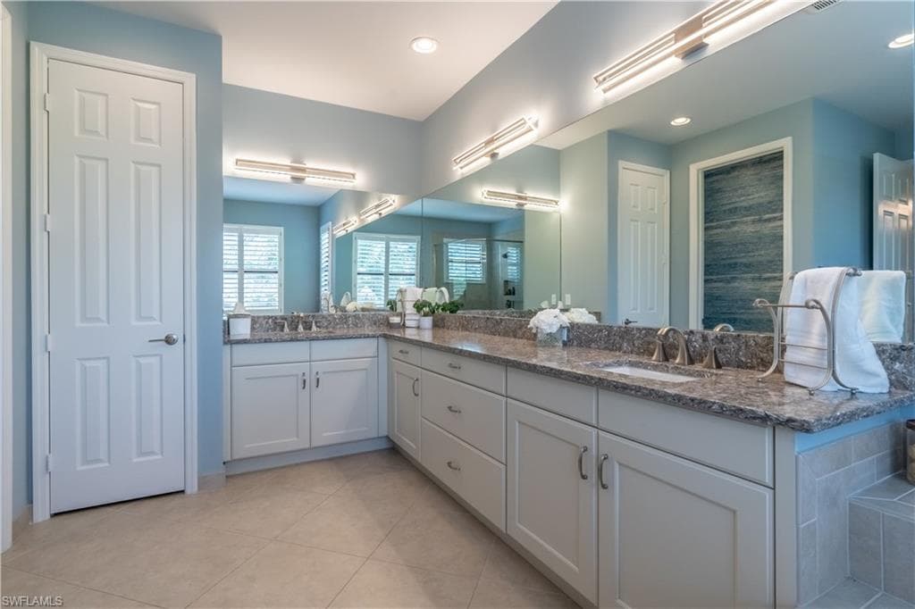 Expansive vanity featuring dual undermount sinks, stone countertops, and extensive mirror space