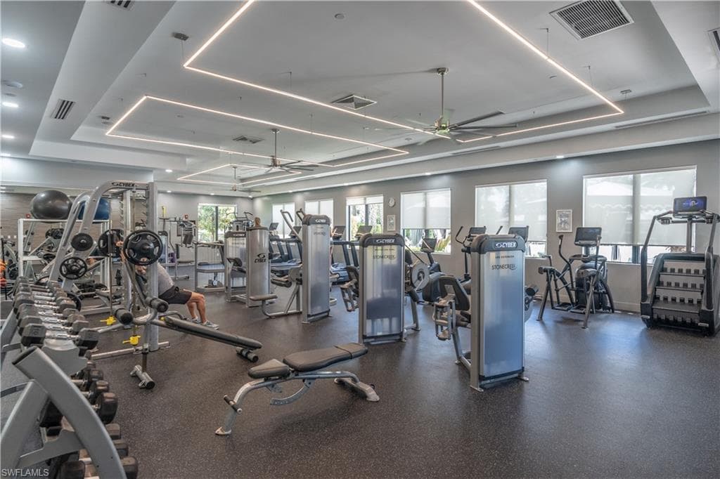 Spacious fitness center featuring recessed lighting, ceiling fans, multiple exercise machines, weight racks, and rubber flooring