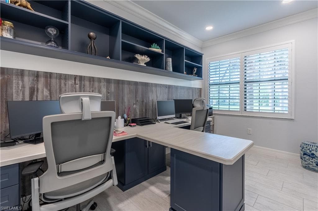 Custom built-in desks with navy cabinetry, wood-finish accent wall, and integrated shelving