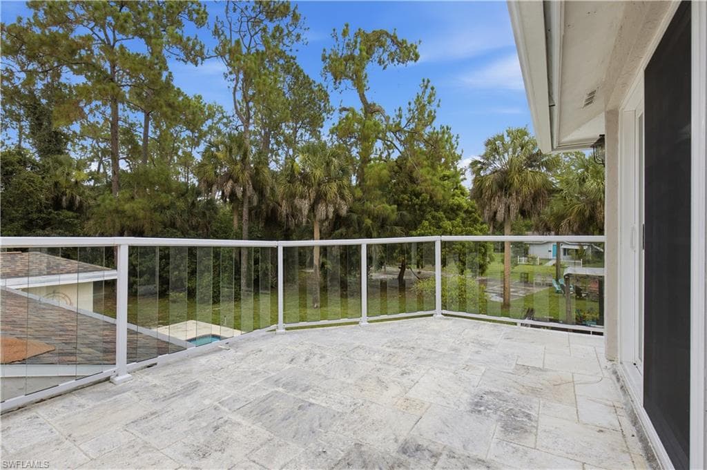 Spacious outdoor terrace with light-toned tile flooring and a glass panel railing system