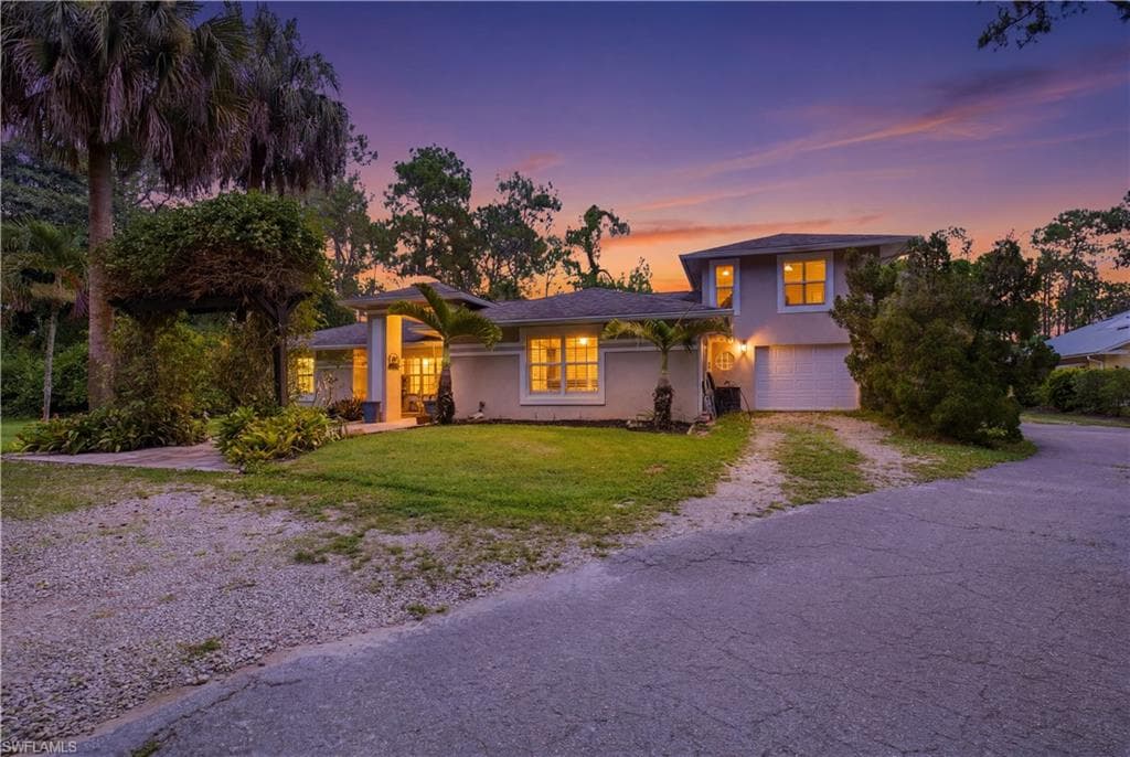 Two-story residence featuring a front entry with a covered porch, an attached garage, and a gravel driveway