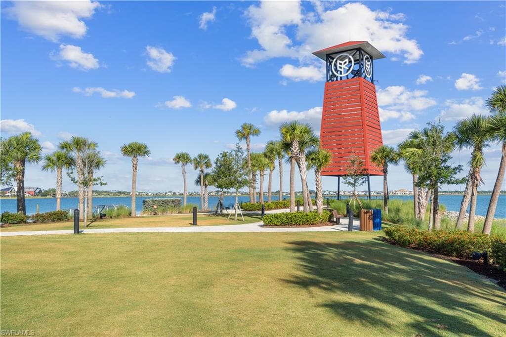 Expansive green space featuring a distinctive red clock tower and established palm trees