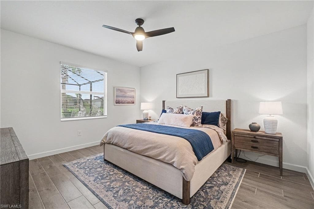 Bright interior space featuring wood-finish flooring, a contemporary ceiling fan with integrated lighting, and a window with blinds