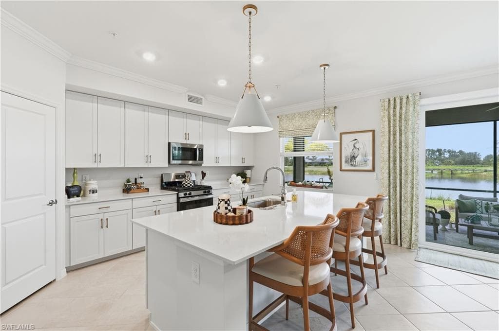 Kitchen with white cabinetry, stainless steel appliances, and a central island with countertop seating