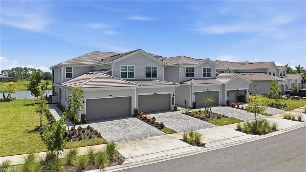 Row of townhomes featuring light gray siding and complementary garage doors