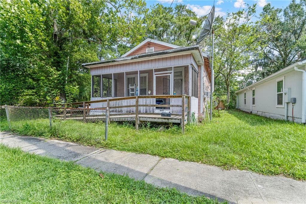 Property exterior featuring a screened porch with a wooden railing and a wooden ramp
