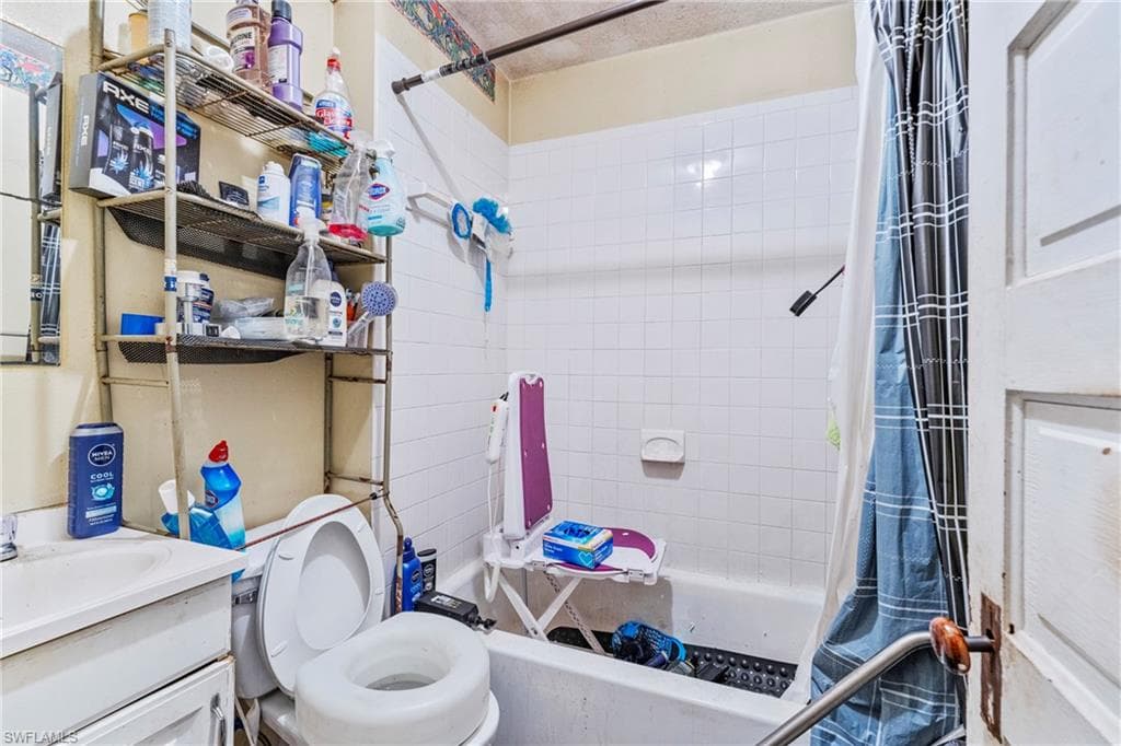 Bathroom featuring a white vanity with an integrated sink, a white toilet, and a bathtub with white subway tile surround