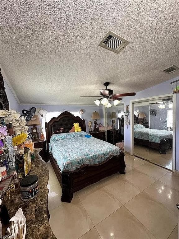 Spacious room featuring tile flooring, a dark wood-finish bed frame, and mirrored closet doors