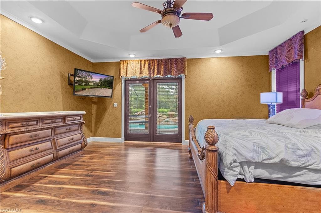 Spacious interior featuring wood-finish flooring, a tray ceiling with recessed lighting, and a ceiling fan