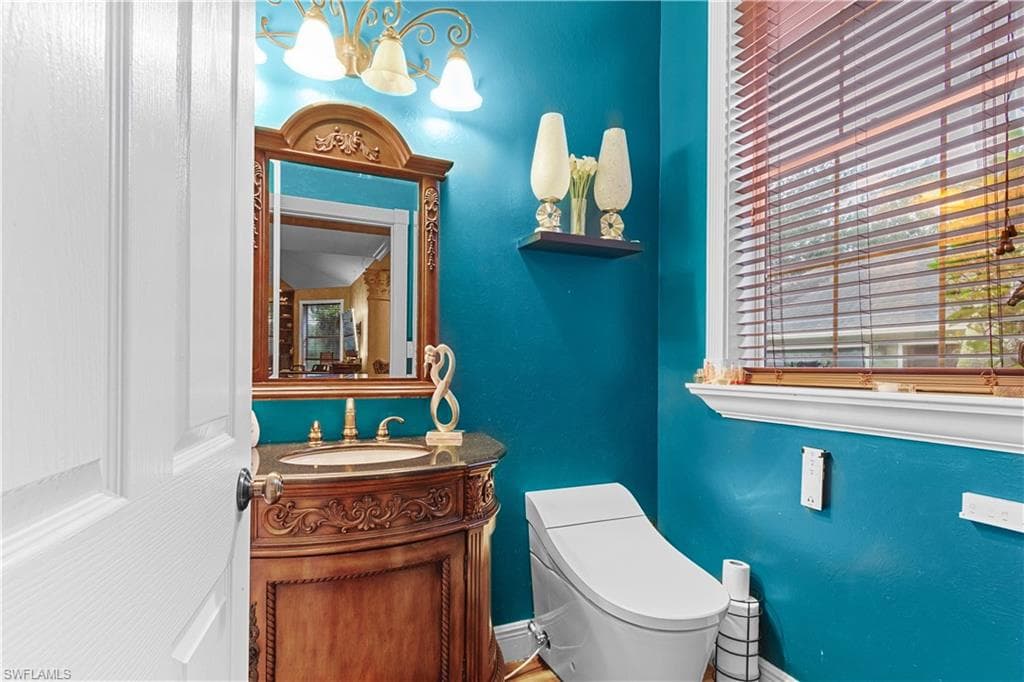 Powder room featuring a carved wood-finish vanity with a stone countertop and an ornate framed mirror