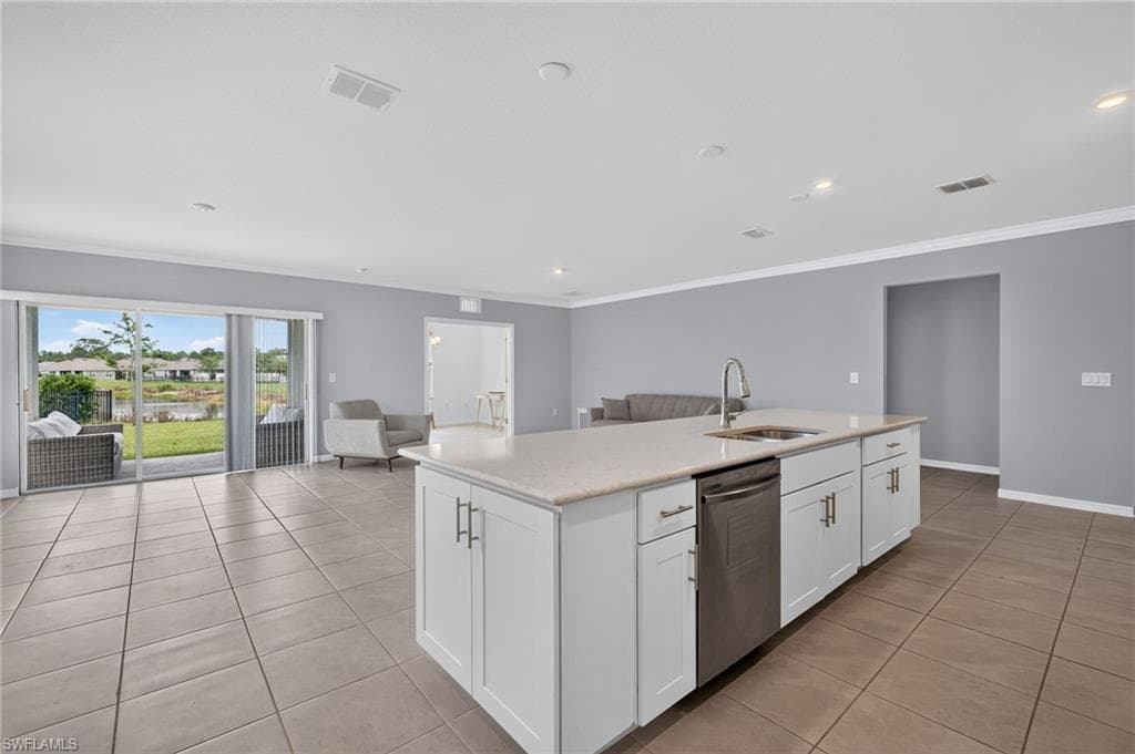 Open-concept living space featuring a spacious kitchen island with integrated sink, stainless steel dishwasher, and white cabinetry