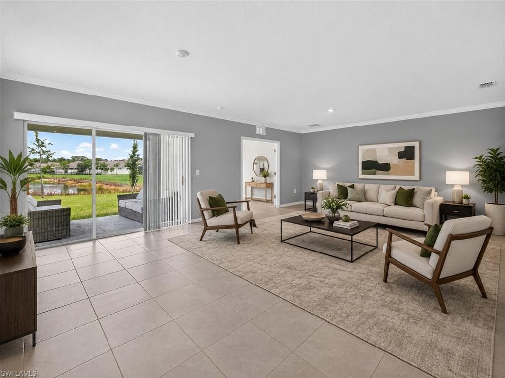 Spacious living area featuring large format tile flooring, crown molding, recessed lighting, and sliding glass doors opening to an outdoor patio