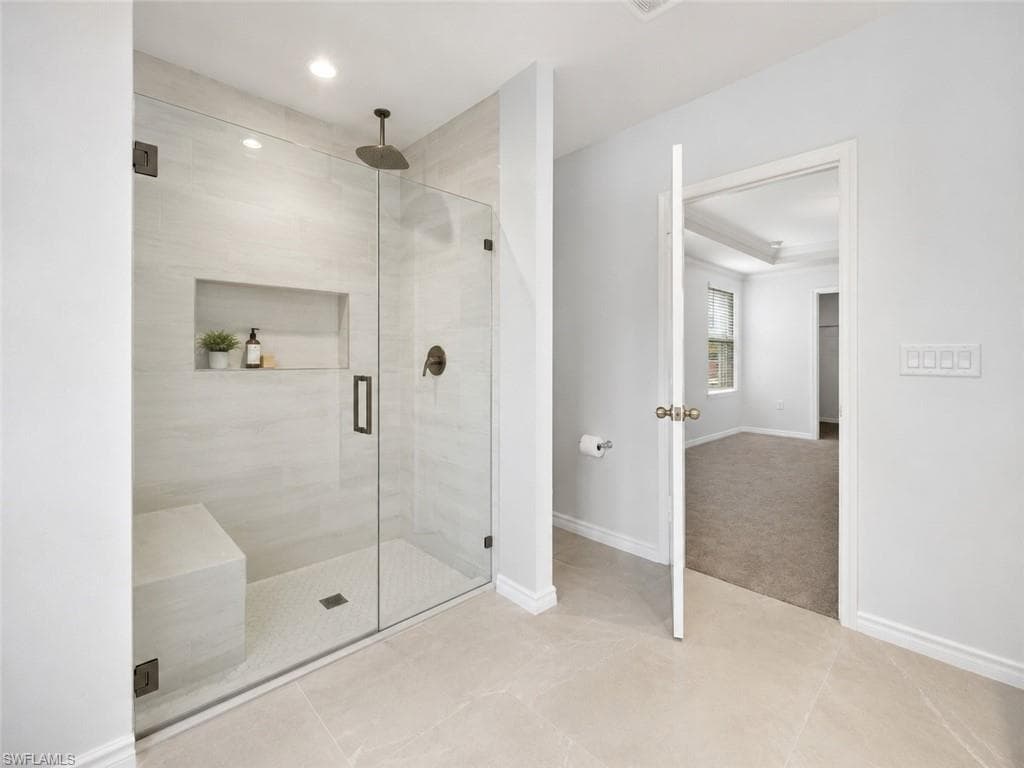 Glass-enclosed shower featuring a built-in bench, recessed niche, rain shower head, and dark bronze fixtures, Virtually Staged