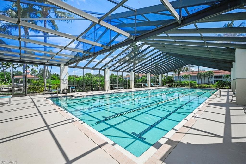 View of swimming pool featuring glass enclosure and a patio area